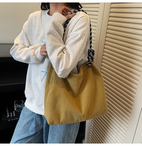 Detail of yellow corduroy tote bag featuring unique black and white checkered strap