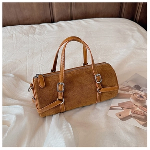 Detail showing brown cylinder suede bucket bag with leather handles and silver buckles