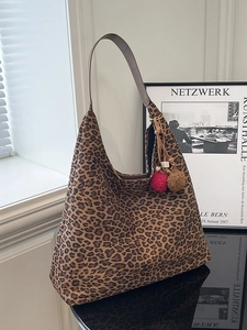 Large leopard print tote bag with brown leather straps and colorful pompom charms