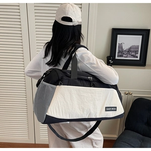Detail of the black and white large travel bag with side mesh pocket and shoulder strap