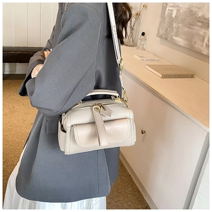 Détails d'un sac à main beige en cuir grainé avec finitions dorées et sangle tissu