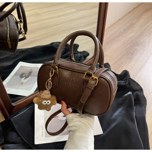 Détail du sac Boston marron foncé avec logo embossé et porte-clé étoile en peluche