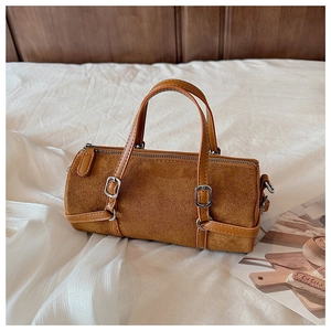 Detail of brown suede cylinder bag with silver metal buckles and retro stitching on fabric