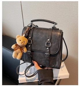 Détail du sac à main vintage en daim gris foncé avec un charmant ours en peluche