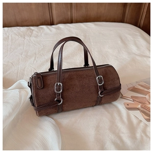 Detail of vintage brown cylinder shoulder bag on soft white fabric with metal zipper