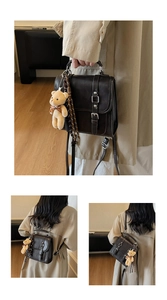 Détail du sac à dos en daim marron avec boucle métallique et pendentif ours en peluche