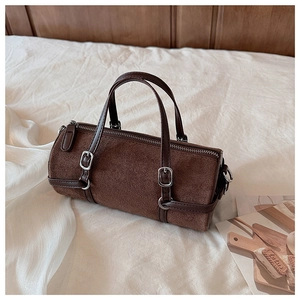 Close-up of brown suede cylinder bag with leather straps and silver metal hardware detail