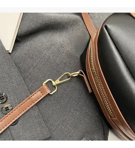 Détail de la quincaillerie dorée et du fermoir mousqueton sur un sac en cuir bicolore