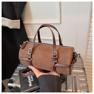 Detail of vintage brown suede cylinder bag featuring leather straps and silver buckle
