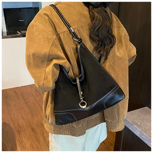 Detail van zwarte matleren hobo tas met witte contraststiksels en een ronde metalen gesp