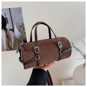 Detail of deep brown suede cylinder bag featuring leather trim and silver metal buckle