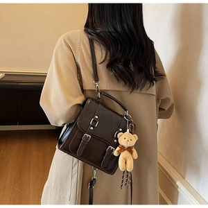 Détail d'un sac à dos vintage en daim marron foncé avec boucles et porte-clé ours