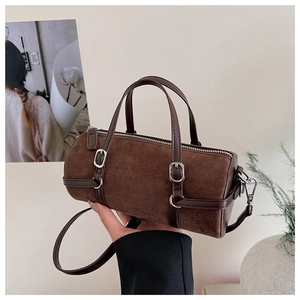 Close-up of vintage brown cylinder bag with suede texture and leather buckle detail