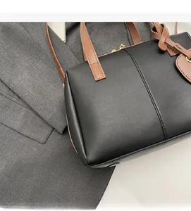 Détail de la texture en cuir souple noir et marron et de la fermeture éclair de ce grand sac
