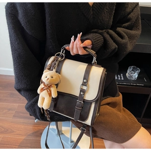 Détail du sac bandoulière en suède bicolore avec un adorable pendentif ours en peluche