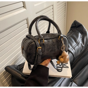 Détail du sac Boston vintage noir avec texture vieillie et breloque en ours peluche