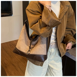 Detail van suède hobo tas met contrasterende lederen bies en decoratieve metalen gesp