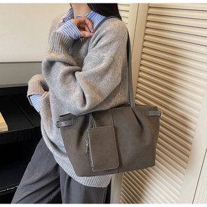 Detail of dark grey tote bag with matching zipper pouch charm and side buckle accent