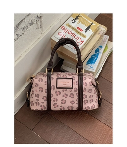 Detailed close-up of pink leopard print Boston bag with dark brown handles and gold hardware