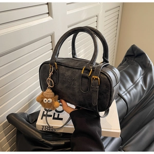 Détail d'un sac polochon rétro noir avec quincaillerie dorée et breloque ours en peluche