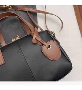 Vue détaillée du sac coquille en cuir noir avec ferrures dorées et bandoulière marron