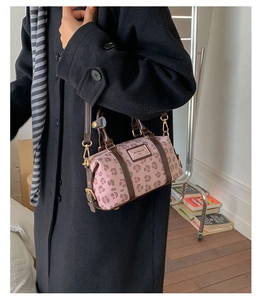 Detailed side view of pink leopard print cylindrical bag with brown leather straps