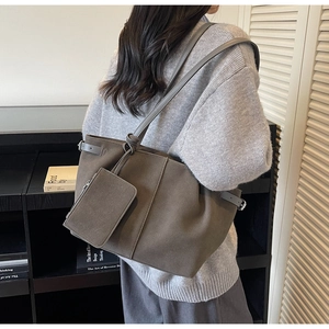 Detail of grey suede tote bag featuring adjustable buckle strap and matching zipper pouch