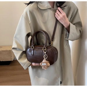 Détail d'un sac Boston vintage marron foncé avec lettrage embossé et bijou de sac peluche