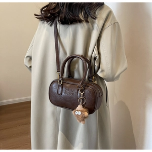 Détail du sac cylindre marron vintage avec gaufrage ARM ARM et pendentif en peluche