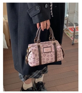 Close-up of pink leopard print cylinder bag with gold hardware and logo plaque