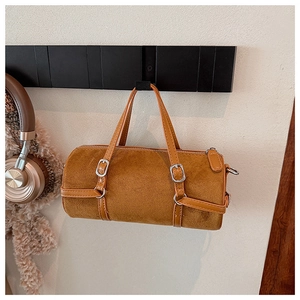 Close-up of brown suede cylinder bag with adjustable leather straps and silver hardware