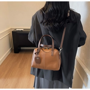 Détail d'un sac à main vintage marron avec deux poignées et un pendentif en cœur