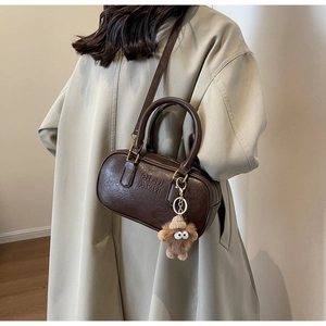 Détail du sac polochon marron vintage avec charm en peluche et style mannequin manteau