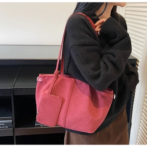 Detail of large dark red suede tote bag featuring matching zipper pouch on model