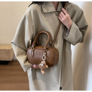 Détail du sac Boston en cuir marron foncé avec gaufrage AIRM et pompon en peluche