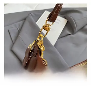 Dettaglio del moschettone dorato e della catena sulla borsa in pelle marrone scuro