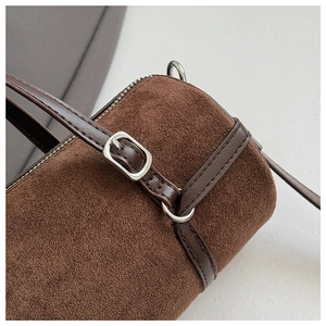 Detailed macro view of dark brown suede cylinder bag with silver metal zipper and buckle