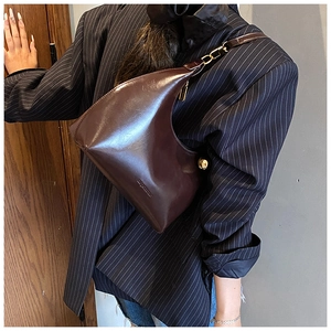 Dettaglio borsa hobo in vernice marrone scuro con cerniera dorata e fibbia in metallo