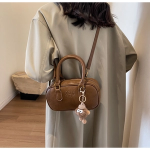 Détail du sac polochon vintage en cuir marron avec logo embossé et breloque en peluche