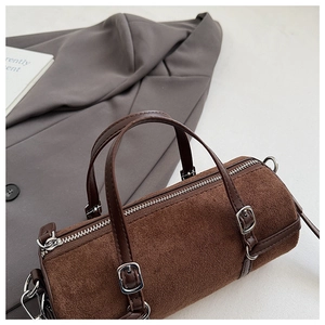 Detail of vintage brown cylinder bucket bag with silver hardware on a grey blazer