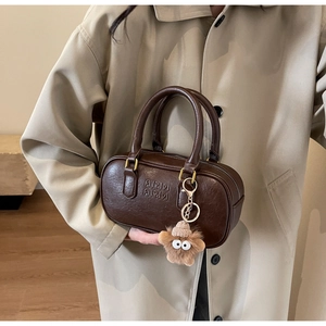 Détail du sac polochon vintage en cuir marron avec fermoir doré et étoile en peluche