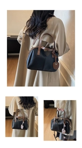 Détail du sac à main noir et marron avec breloque cœur et multiples modes de transport