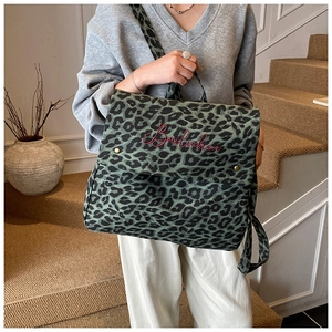 Detail of green leopard canvas backpack with red embroidery on a stylish urban background