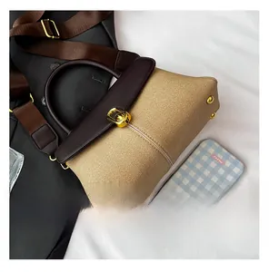 Detail view of khaki canvas handbag with brown leather trim and gold twist-lock closure
