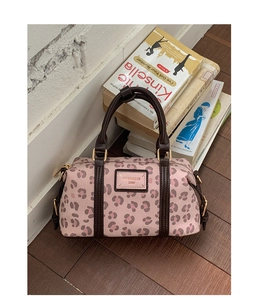 Close-up of pink leopard print Boston bag with leather handles and gold-tone hardware