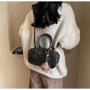 Détail du sac Boston gris foncé avec gaufrage de la marque et pendentif en peluche