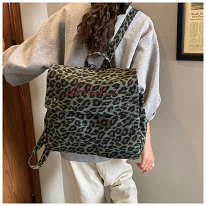 Detailed view of leopard print backpack featuring red embroidery and olive canvas texture