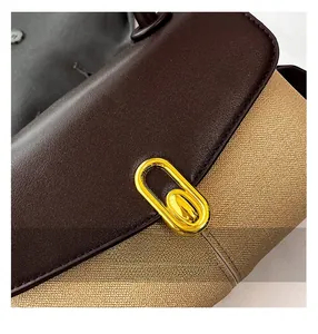 Close-up of contrast brown leather flap and canvas body with gold oval metal lock