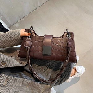 Detail of dark brown crocodile pattern shoulder bag with stylish woven handle and clasp