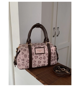 Detail of pink leopard print boston bag with brown leather handles and gold hardware